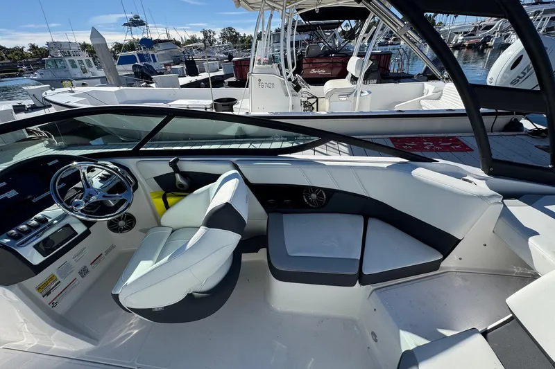 Slide: The Image of 2026 Regal 21 OBX boat interior with modern seating and steering, docked at marina. - 15