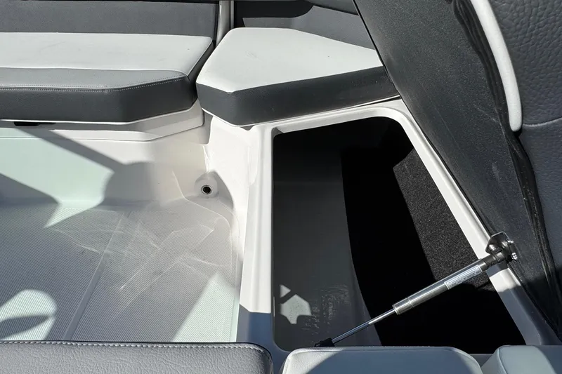 Slide: The Image of 2026 Regal 21 OBX boat interior storage compartment with cushioned seating. - 26