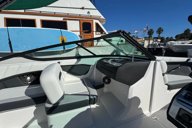 Slide: The Image of 2026 Regal 21 OBX boat interior with seating and dashboard, docked near other boats. - 29