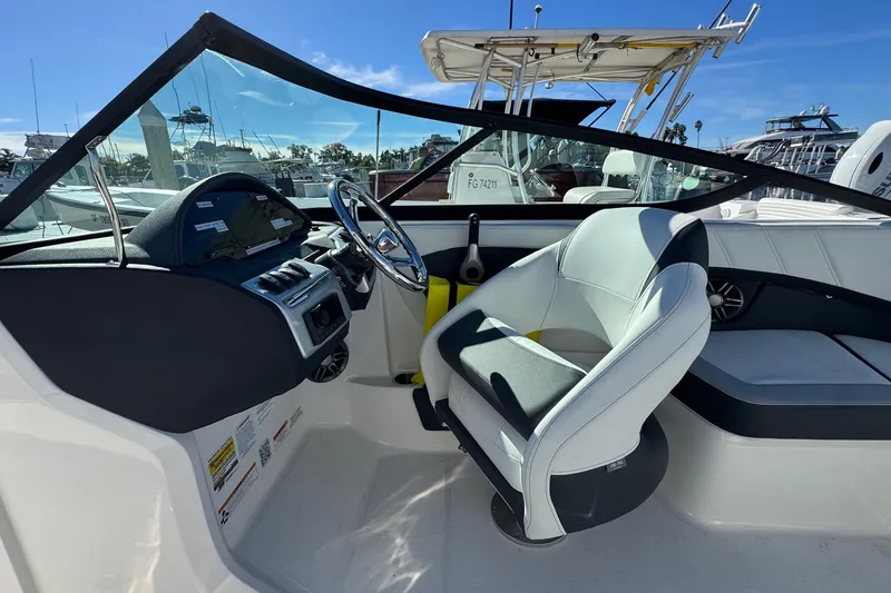 Slide: The Image of 2026 Regal 21 OBX boat interior with steering wheel and seating, docked at marina. - 33