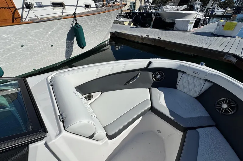 Slide: The Image of Interior of 2026 Regal 21 OBX boat with white and gray seating at a marina. - 45