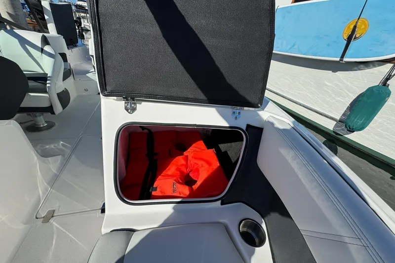 Slide: The Image of Open storage compartment on 2026 Regal 21 OBX boat with life jackets inside. - 47