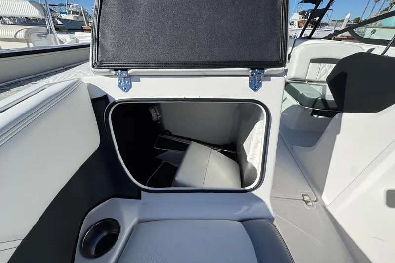 Slide: The Image of 2026 Regal 21 OBX boat interior storage compartment with open hatch and cup holder. - 51