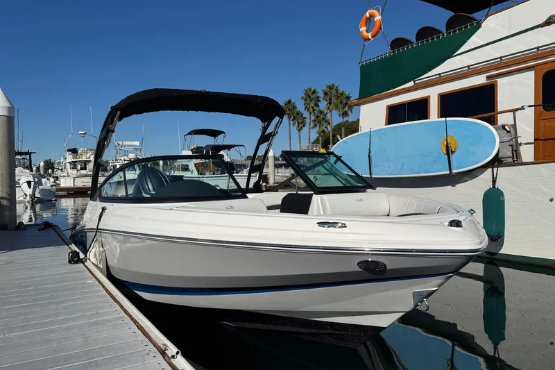 Slide: The Image of 2026 Regal 21 OBX boat docked at marina, clear sky, paddleboard nearby. - 7