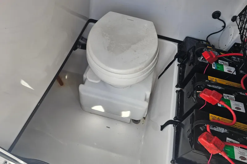 Slide: The Image of 2021 Sportsman Masters 267OE Bay Boat interior with portable toilet and battery setup. - 34