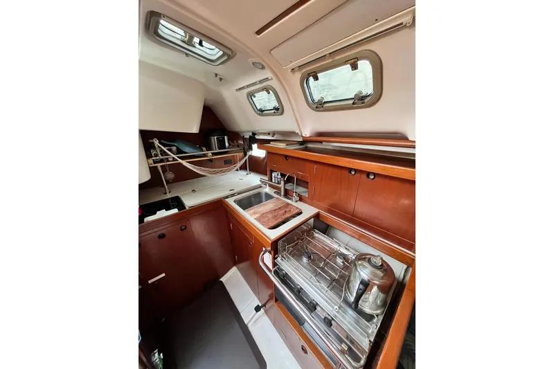 Slide: The Image of 1995 Beneteau Oceanis 351 yacht kitchen with wooden cabinetry and stainless steel appliances. - 13