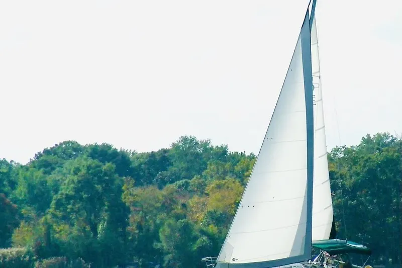 Slide: The Image of Sailing yacht Beneteau Oceanis 351, 1995 model, cruising near lush green shoreline. - 2