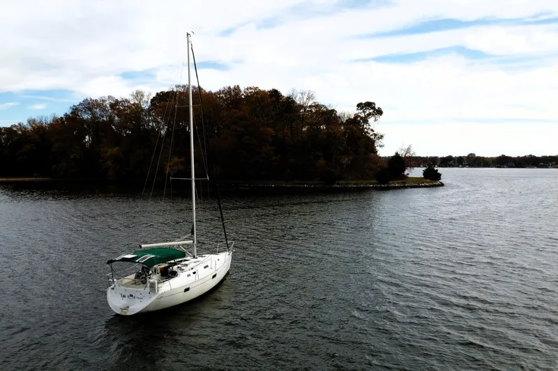Slide: The Image of Sailboat Beneteau Oceanis 351 (1995) anchored near a wooded island on a calm lake. - 5