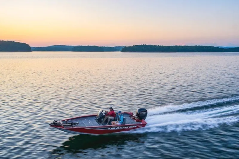 Slide: The Image of 2025 Tracker Pro Team 195 Tournament Edition boat cruising on a serene lake at sunset. - 14