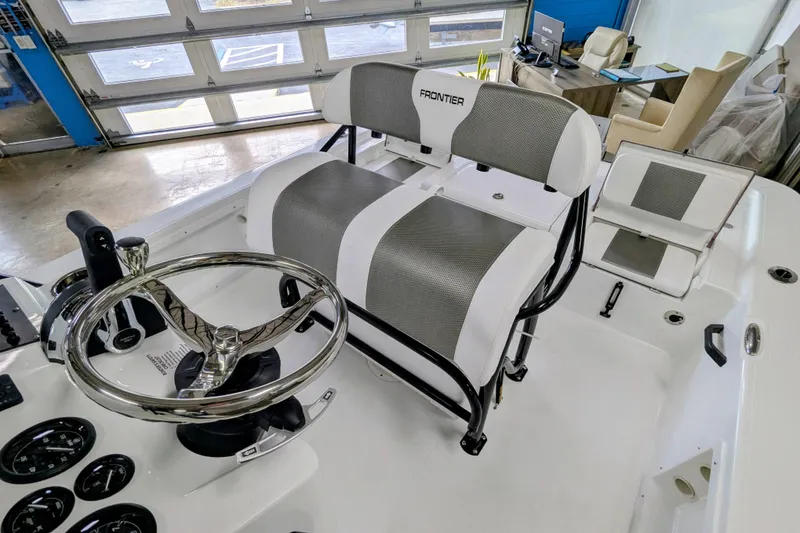 Slide: The Image of 2026 Frontier 2104 boat interior with steering wheel and seating in showroom. - 8