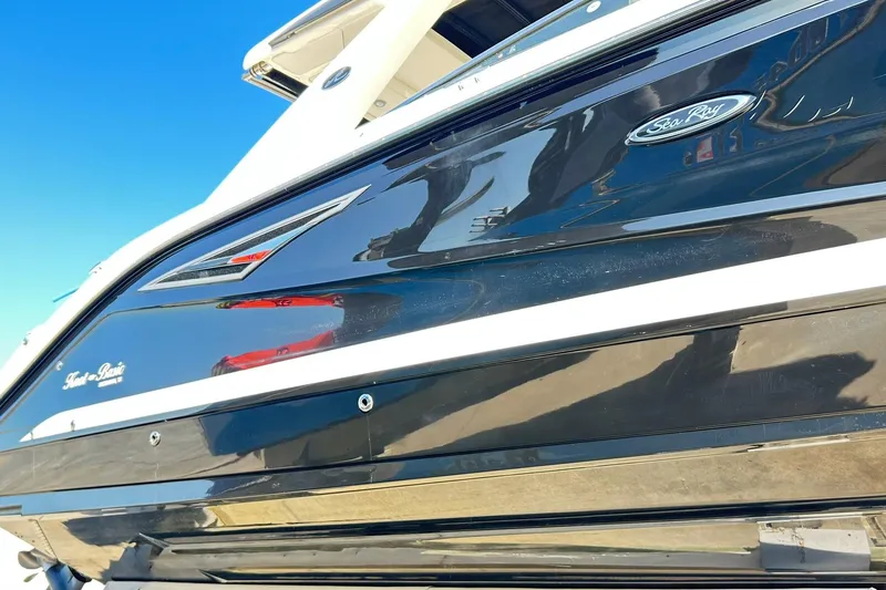 Slide: The Image of 2020 Sea Ray SLX 310 boat, sleek black exterior with logo, under clear blue sky. - 2