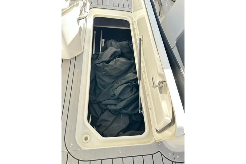 Slide: The Image of Open storage compartment on 2020 Sea Ray SLX 310 boat, showing interior contents. - 27