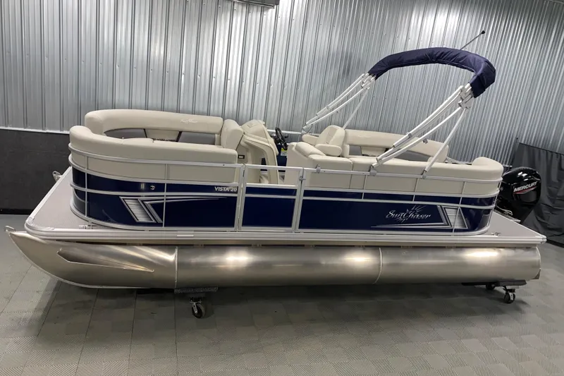 The Image of 2026 SunChaser Vista 20 LR pontoon boat in a showroom with blue and white design. - 0
