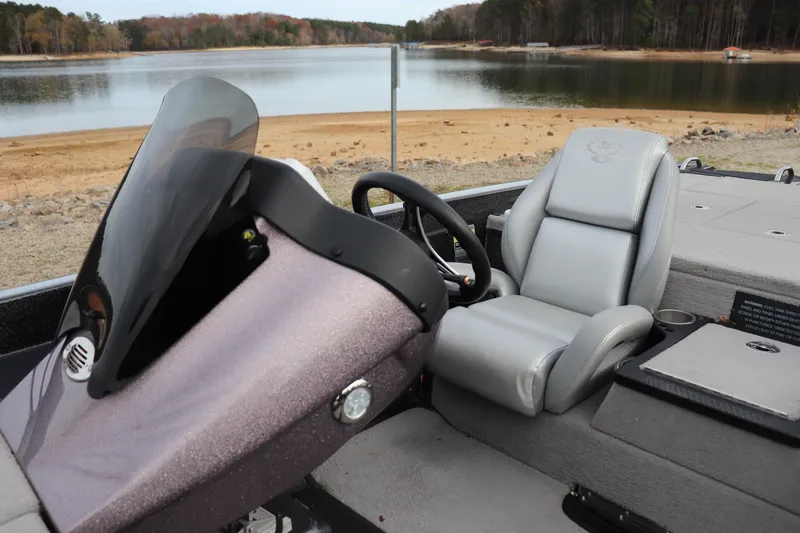 Slide: The Image of 2020 Phoenix 21 PHX boat interior with steering wheel and seat by a lake. - 5