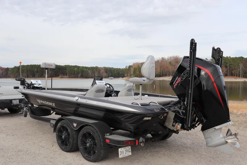 Slide: The Image of 2020 Phoenix 21 PHX boat on trailer by a lake, featuring powerful outboard motor. - 8