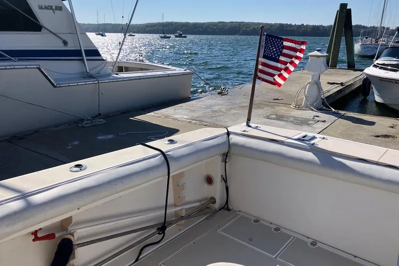 Slide: The Image of 2000 Albin 28 Tournament boat docked, featuring an American flag, with scenic waterfront view. - 9