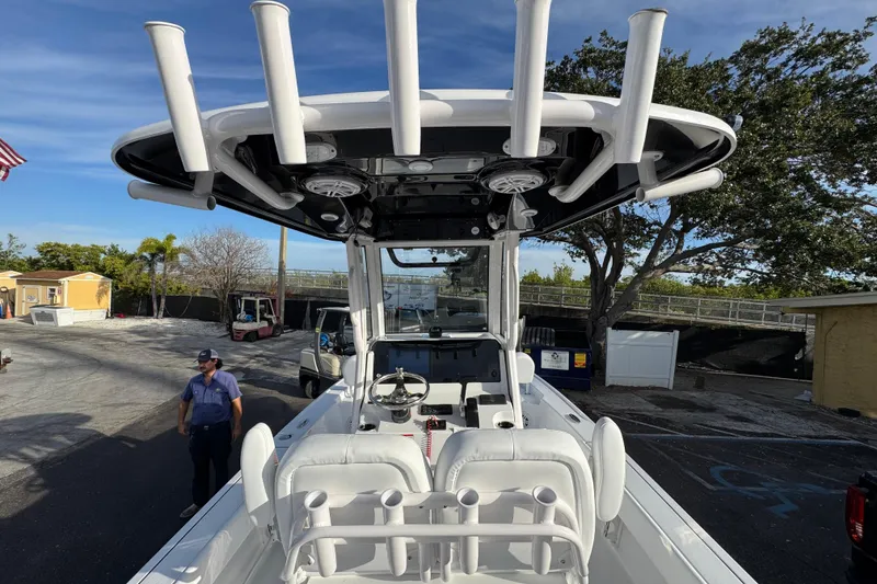 Slide: The Image of 2026 Sportsman Masters 227 Bay Boat with T-top and rod holders, parked outdoors. - 6