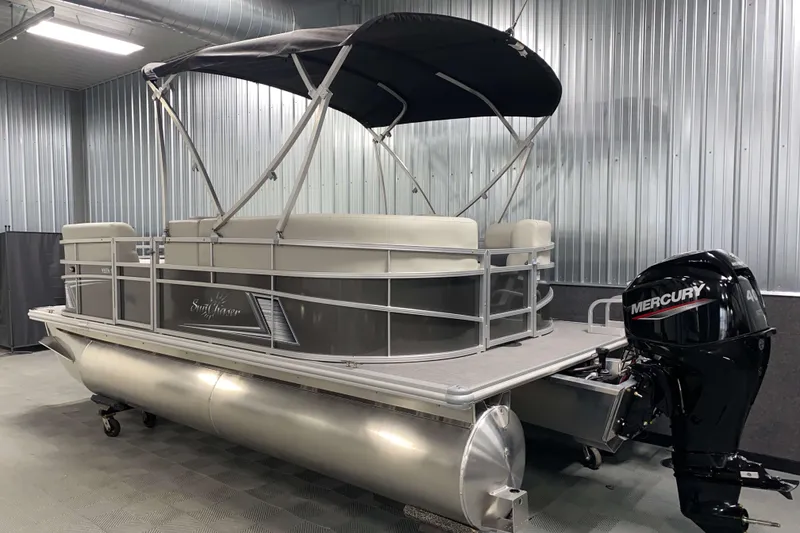Slide: The Image of 2026 SunChaser Vista 18 LR pontoon boat with Mercury outboard motor in a metal-walled showroom. - 16