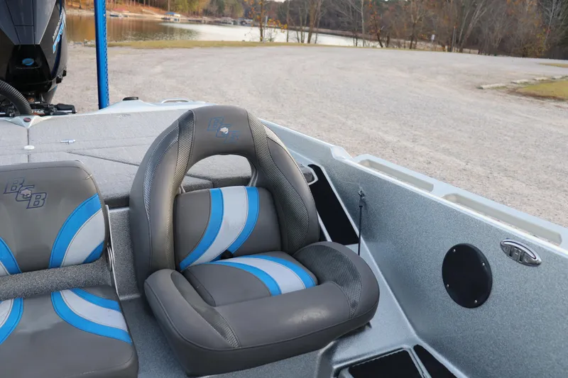 Slide: The Image of 2019 Bass Cat Lynx boat interior with gray and blue seating near a lake. - 11