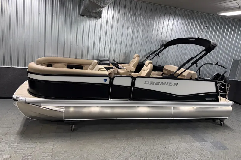 The Image of 2026 Premier 230 Sunsation RL Tritoon in showroom, featuring sleek design and beige seating. - 0