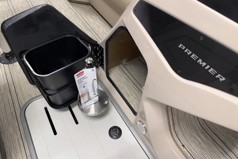 Slide: The Image of 2026 Premier 230 Sunsation RL Tritoon interior with storage bin and faucet packaging. - 19