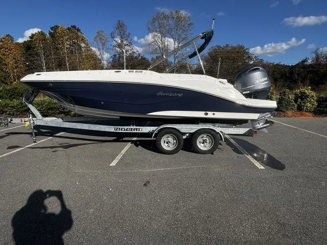 The Image of 2023 Hurricane SunDeck Sport 205 OB boat on trailer in parking lot, clear sky background. - 1