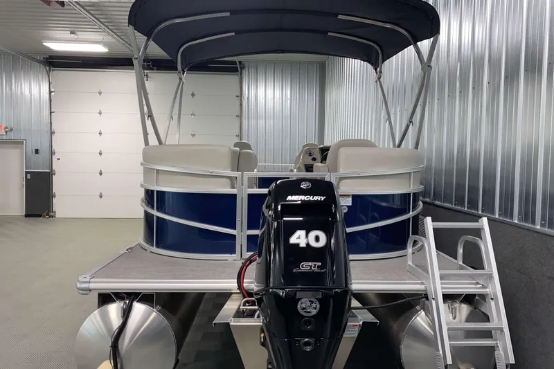 Slide: The Image of 2026 SunChaser Vista 18 Fish pontoon boat with Mercury 40 engine in a metal garage. - 21