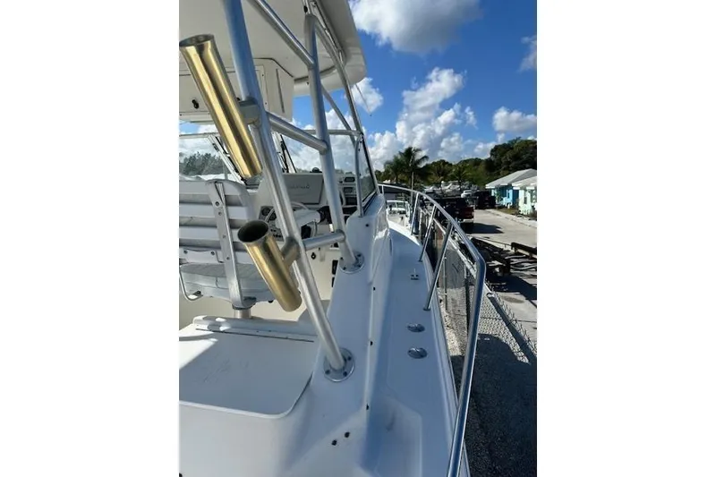 Slide: The Image of 2005 Sea Fox 287 Walkaround boat with rod holders, docked under a clear blue sky. - 4