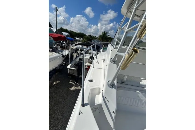 Slide: The Image of 2005 Sea Fox 287 Walkaround boat with sleek deck and railing, under a sunny sky. - 5