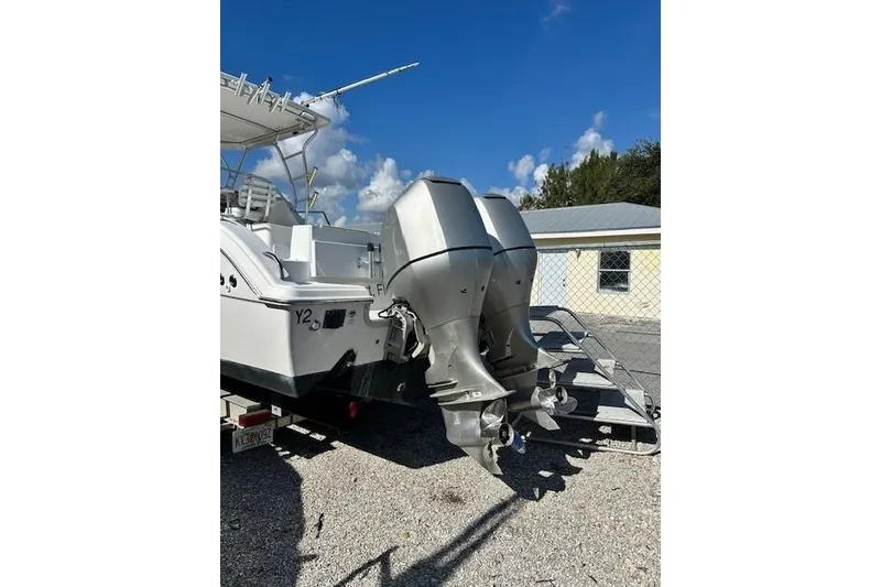 Slide: The Image of 2005 Sea Fox 287 Walkaround boat with dual outboard motors, parked on gravel. - 7