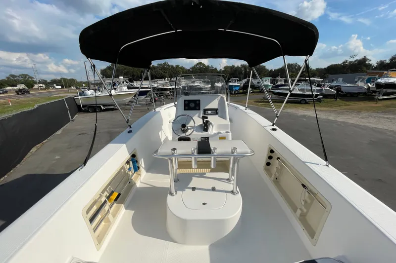 Slide: The Image of 2004 Fishmaster Travis Edition 220 boat with canopy, docked in a marina under a blue sky. - 13