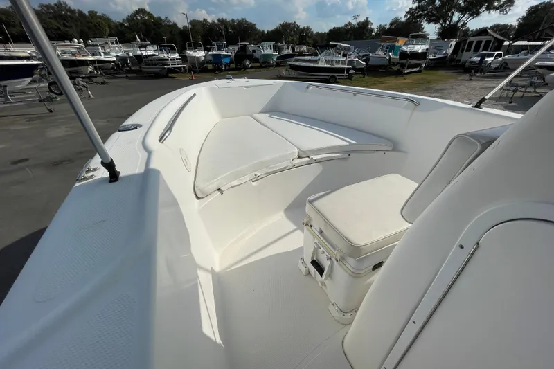 Slide: The Image of 2004 Fishmaster Travis Edition 220 boat interior with seating and cooler, docked among other boats. - 34