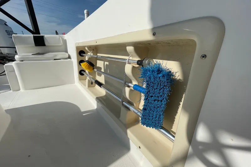 Slide: The Image of Storage compartment with cleaning brushes on a 2004 Fishmaster Travis Edition 220 boat. - 49