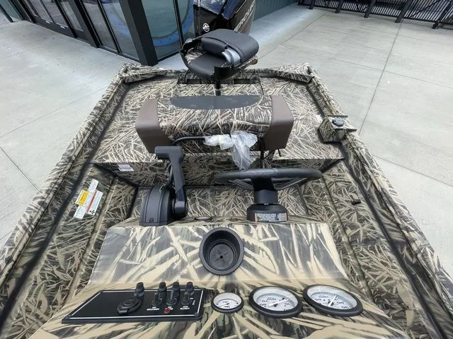 Slide: The Image of 2023 Crestliner 1860 Retriever CC boat with camo design, featuring steering console and gauges. - 9