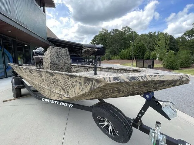 Slide: The Image of 2023 Crestliner 1860 Retriever CC boat on trailer, camo design, parked outdoors. - 3