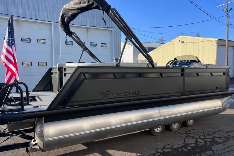 Slide: The Image of 2026 Viaggio V 20U pontoon boat with American flag, parked outside industrial building. - 4