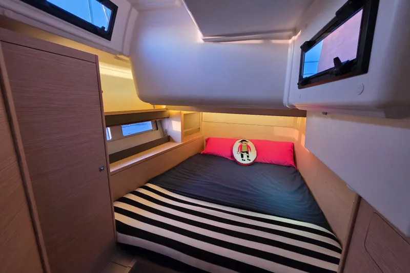 Slide: The Image of 2024 Dufour 530 yacht cabin with cozy bed, striped blanket, and nautical decor. - 16