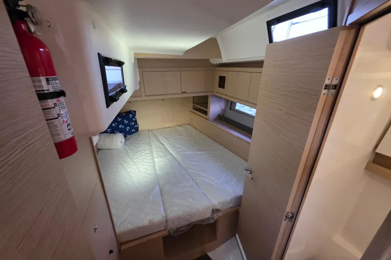 Slide: The Image of 2024 Dufour 530 yacht cabin with bed, wooden cabinetry, and fire extinguisher. - 17
