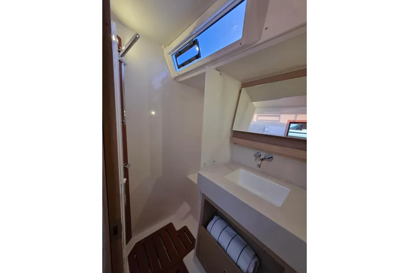 Slide: The Image of 2024 Dufour 530 yacht bathroom with modern sink, mirror, and window. - 22