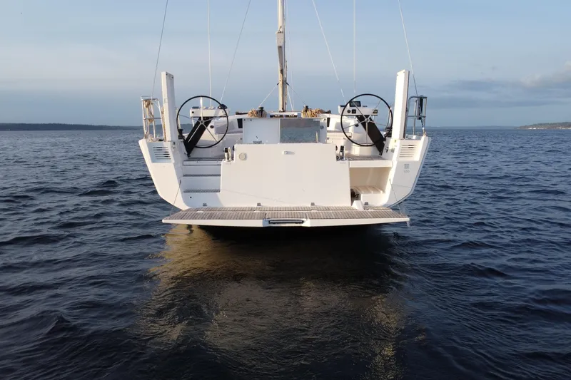 Slide: The Image of 2024 Dufour 530 yacht on calm waters, rear view showcasing dual steering wheels. - 4