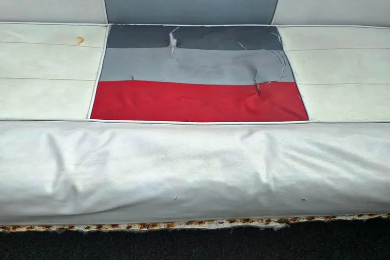Slide: The Image of Worn upholstery on 1991 Rinker 236 Captiva Cuddy Cabin boat seat, showing tears and discoloration. - 22