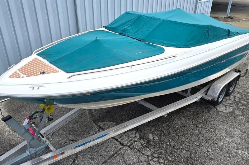 Slide: The Image of 1995 Sea Ray 240 Bow Rider boat on trailer with teal cover. - 17