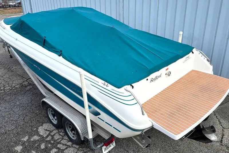 Slide: The Image of 1995 Sea Ray 240 Bow Rider boat with teal cover on trailer. - 18
