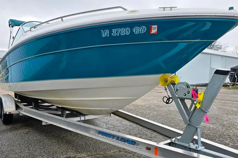 Slide: The Image of 1995 Sea Ray 240 Bow Rider on trailer, blue and white hull, parked outdoors. - 19