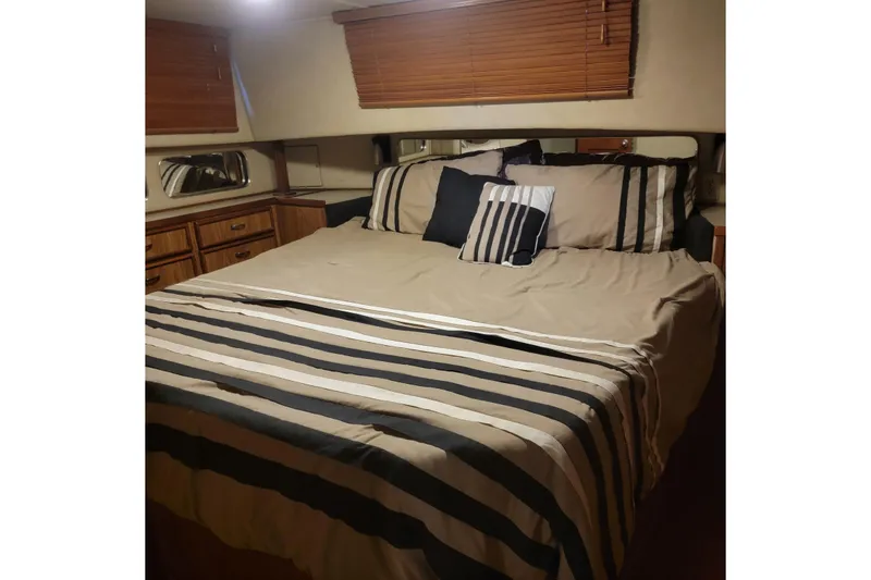 Slide: The Image of 1988 Chris-Craft 381 Catalina bedroom with striped bedding and wooden blinds. - 13