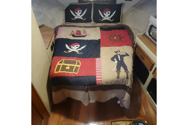 Slide: The Image of Pirate-themed bedding in 1988 Chris-Craft 381 Catalina cabin, featuring skulls and treasure chest designs. - 16