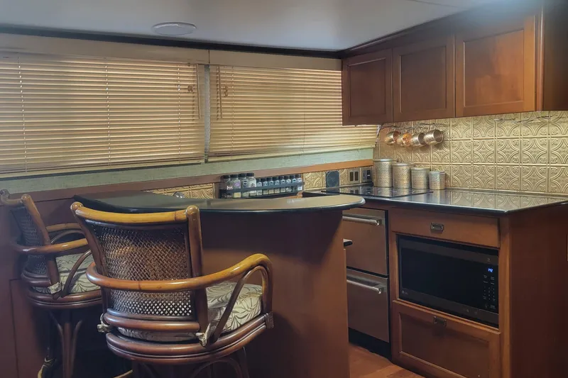 Slide: The Image of 1988 Chris-Craft 381 Catalina yacht interior with kitchen, bar stools, and wooden cabinetry. - 8