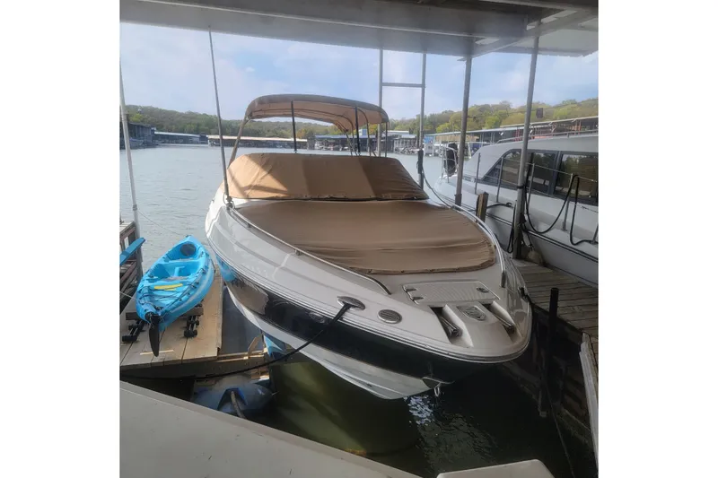 The Image of 2005 Chaparral 256 SSi boat docked with blue kayak nearby, under canopy. - 0