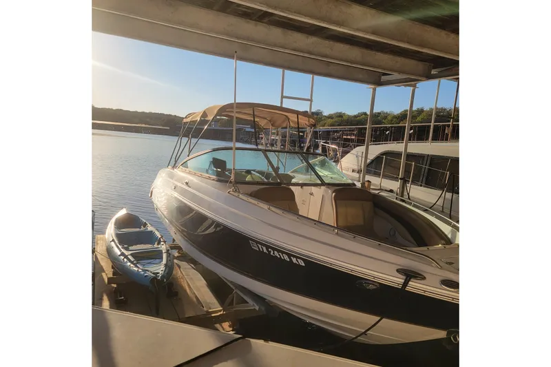Slide: The Image of 2005 Chaparral 256 SSi boat docked with a kayak, under a sunny sky. - 4