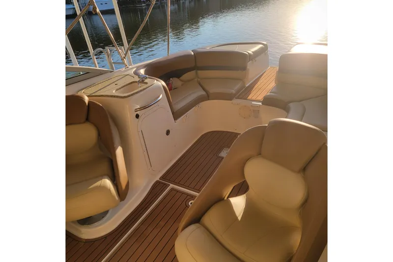 Slide: The Image of 2005 Chaparral 256 SSi boat interior with tan seating and wood flooring, near water. - 9